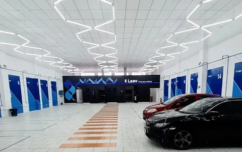 Foto real do interior de uma unidade Laav, com vagas numeradas, iluminação geométrica e veículos.